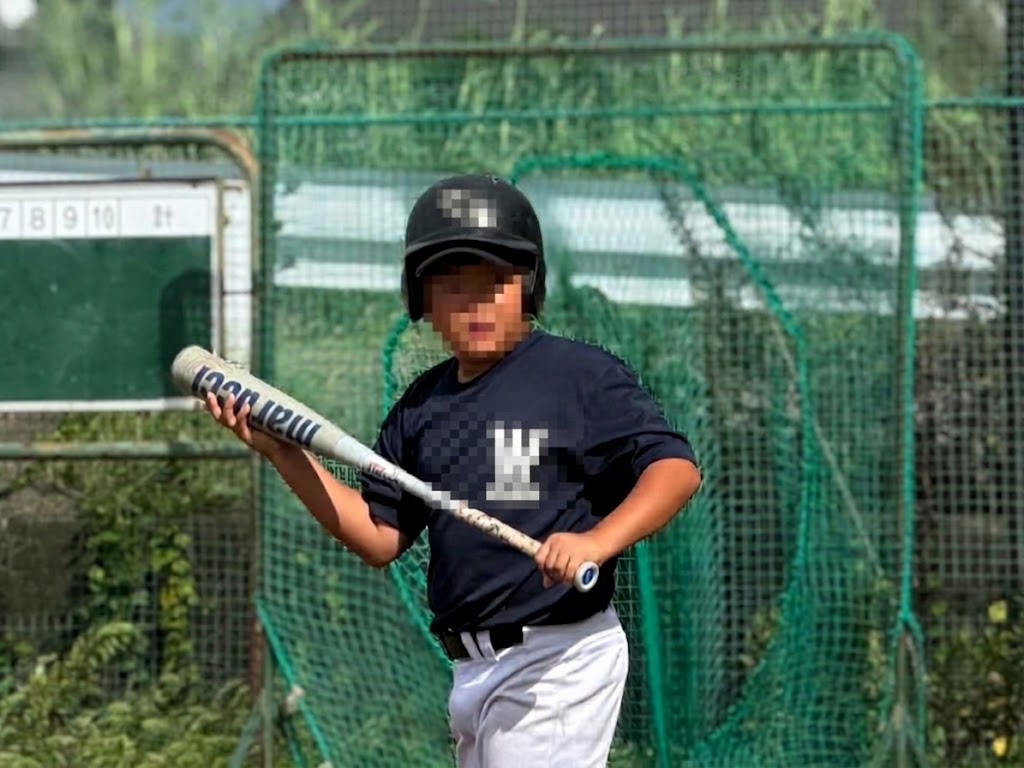 ヘルメットを着用しバットを両手で持つ少年野球の選手