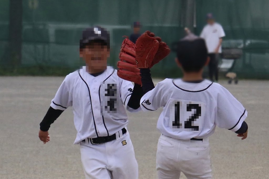 グラウンドでグローブを合わせて喜ぶ少年野球の選手たち